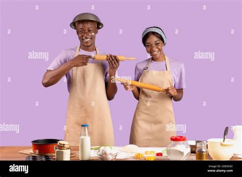 Positive Black Couple With Rolling Pins Having Fun While Cooking