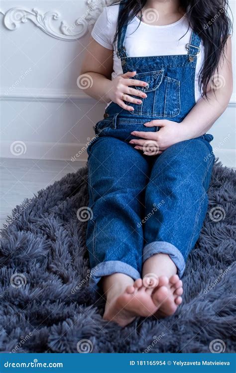 Pregnant Woman In Blue Denim Overalls And White T Shirt Sitting On The Floor Stock Photo Image