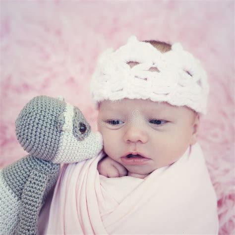 Portrait Of Newborn Baby Girl Wrapped In Pink Wrap With Knitted Woolen