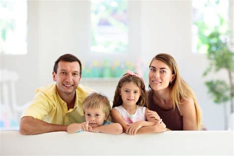 Familia Feliz En Casa Padres E Hijos En El Sofá Imagen De Archivo