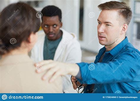 Male Psychologist Comforting Patient In Support Group Stock Photo