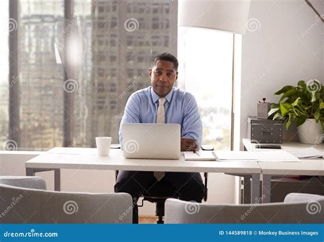 Portrait Of Male Financial Advisor In Modern Office Sitting At Desk