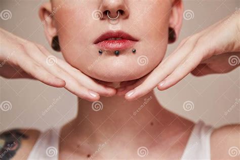 woman with piercing at her face and ear tunnels posing with hands near her face stock image