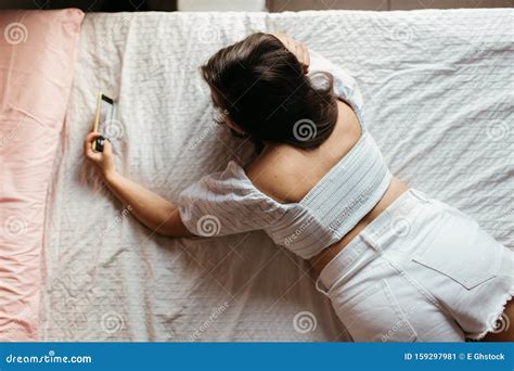 Top View Of Young Sad Woman Lying On The Bed Looking Smartphone Feels Unhappy Waiting For