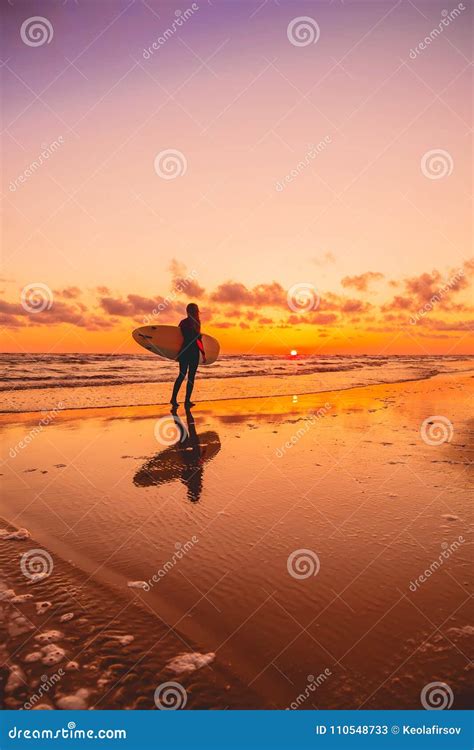 Silhouette With Surfer Girl And Surfboard On A Beach At Warm Sunset Or