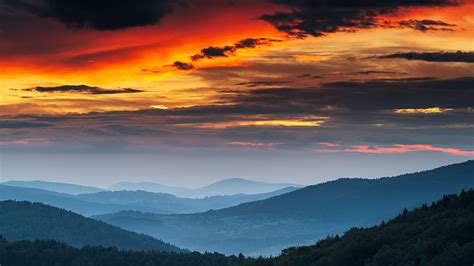 Green Covered Mountains Under Reddish Black Cloudy Sky During Sunset