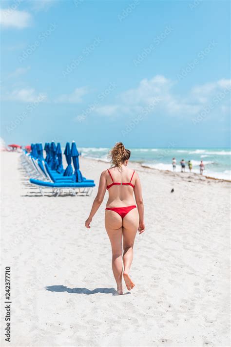 Young Woman In Red Swimsuit Bikini Thong On Beach During Sunny Day In Miami Florida Resort Blue