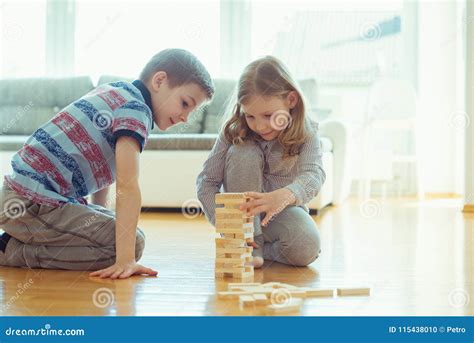 Two Happy Siblings Playing A Game With Wooden Blocks At Home Stock