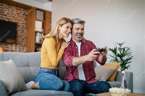 Premium Photo Happy Mature European Wife Hugging Husband With Joystick Enjoy Online Game On
