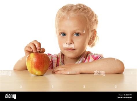 Funny Little Girl Hiding Behind Table And Looking At Apple Stock Photo
