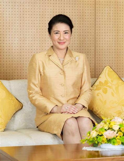 A Woman Sitting On Top Of A White Couch Next To A Vase With Yellow Flowers