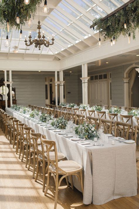 A Long Table Is Set Up With White Linens And Greenery
