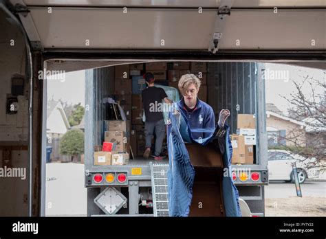 Two Young Caucasian Men Employees Of A Moving Company Load Furniture In