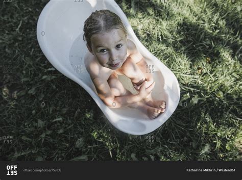 Portrait Of Babe Girl Sitting In Bath Tub In Garden Stock Photo OFFSET
