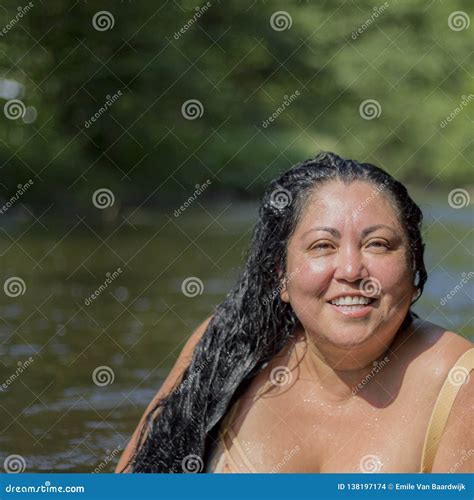 Chubby Mexican Woman Smiling At The Camera With Green Vegetation In A Blurred Background Stock