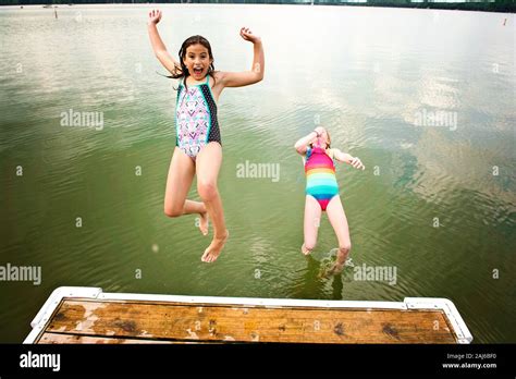 Zwei Junge Mädchen In Badeanzügen Springen Von Einem Dock In Einen See Stockfotografie Alamy