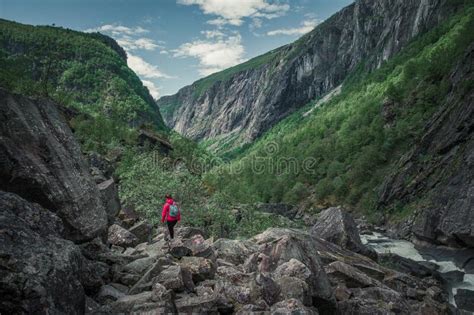Woman Hiking Along River In The Valley Of Voringsfossen Waterfall At