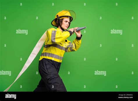 photo of serious reliable firewoman dressed yellow uniform helmet holding fire hose looking