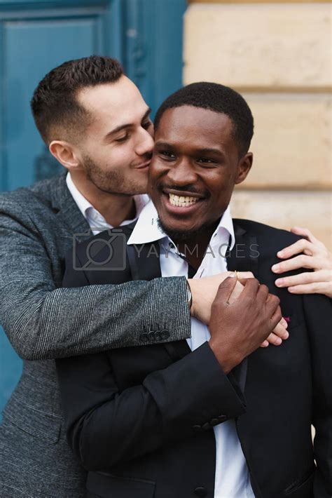 Two Men Caucasian And Afro American Wearing Suits Standing Near Building And Hugging Same Sex