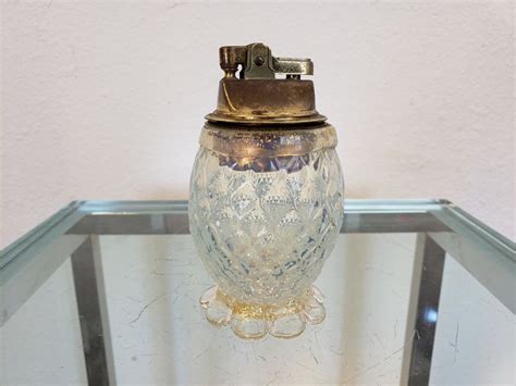 A Glass Jar With A Metal Clip On It Sitting On A Glass Shelf In Front