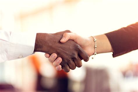 Closeup Of White And Black Shaking Hands Over A Deal Stock Photo