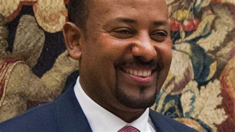 A Close Up Of A Person Wearing A Suit And Tie With A Smile On His Face