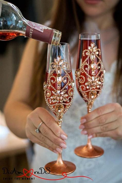 a woman is pouring wine into two champagne glasses with red and gold