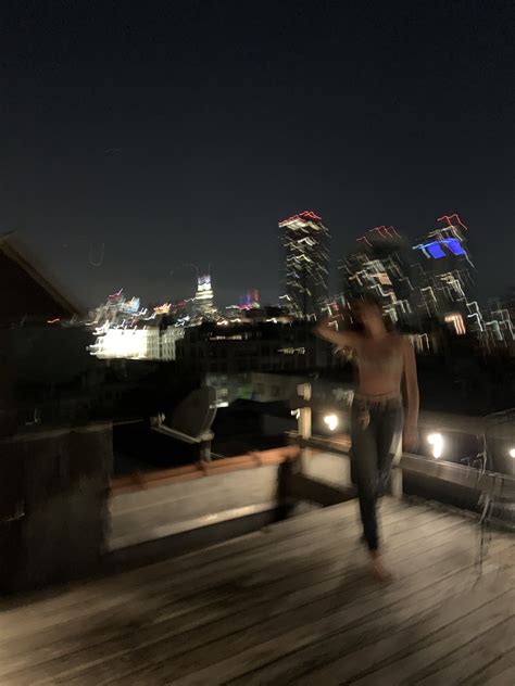 A Man Walking On A Wooden Deck In Front Of A Cityscape At Night