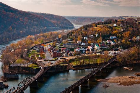 An Aerial View Of A Town And Bridge Over A River With Autumn Foliage In