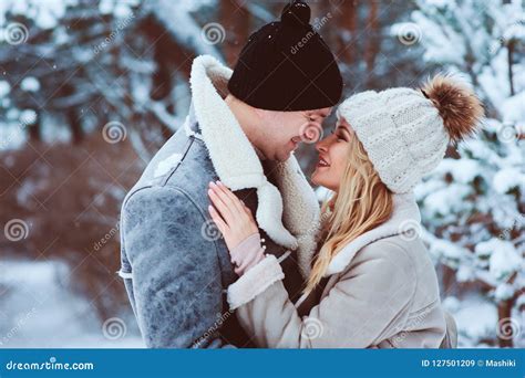 Winter Portrait Of Happy Romantic Couple Embracing And Looking To Each Other Outdoor In Snowy