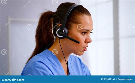 Portrait Of Medical Receptionist Answering Pressing On Headphone Stock