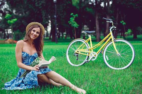 Beautiful Young Woman Portrait Reading A Book With Bicycle In The Park