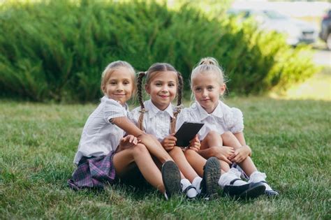 Drie Meisjes Zitten Op Het Gras En Lezen Een Ebook Leerlingen Van Lage School Begin Van Lessen