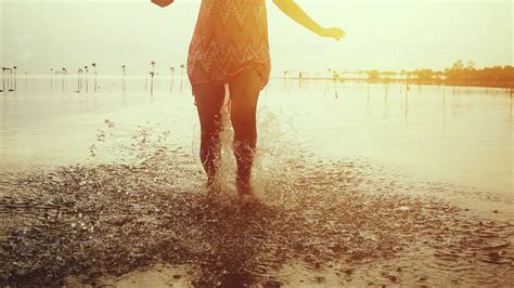 Young Woman In Short Dress Running On The Beach During Beautiful Sunset