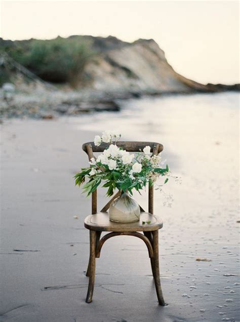 A Chair With Flowers In It Sitting On The Beach