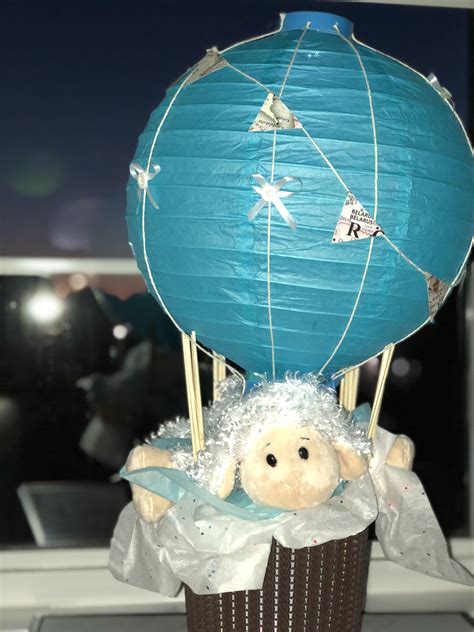 A Stuffed Sheep In A Basket With A Blue Paper Lantern On Its Head