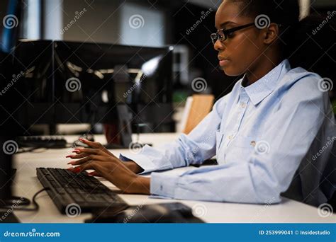 African Young Woman Typing On A Computer At Her Desk In The Office