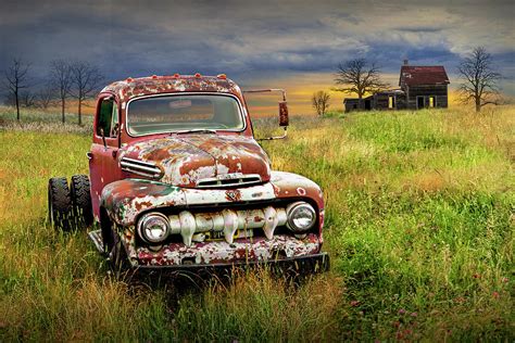 Rusted Vintage Ford Truck In A Grassy Field By An Abandoned Farm