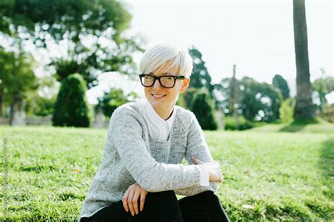 Blonde Woman Wearing Rimmed Glasses Sitting On The Park By