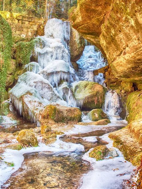 Long Exposure Of The Iced Waterfall Frozen Stream Between Mossy Rocks
