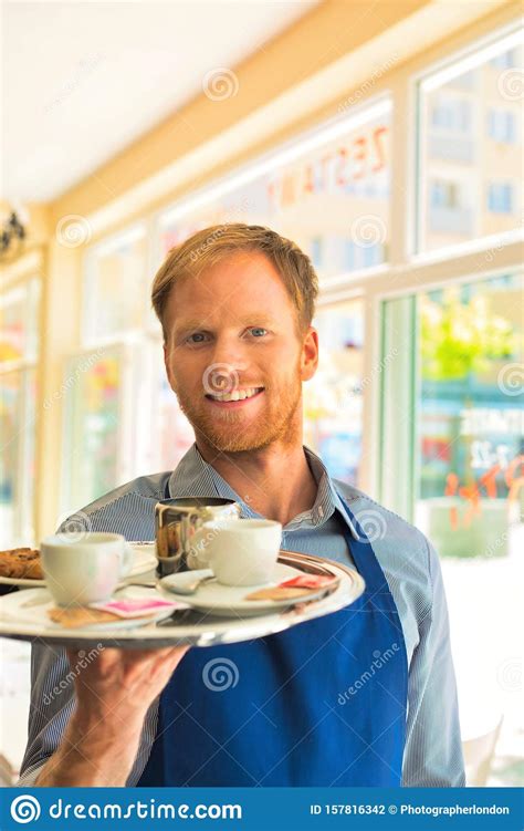 Young Waiter Serving Coffee And Cookies At Restaurant Stock Photo