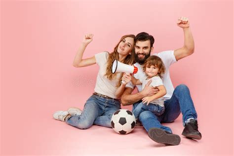 Happy Father And Son Playing Together With Soccer Ball On Pink Stock