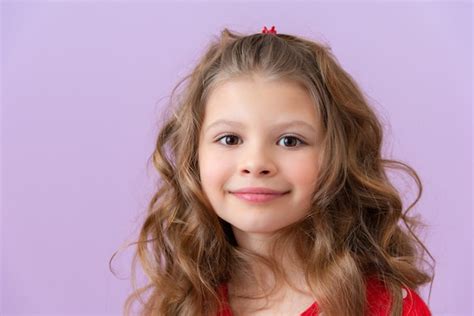 Улыбается красивая маленькая девочка с вьющимися волосами Премиум Фото