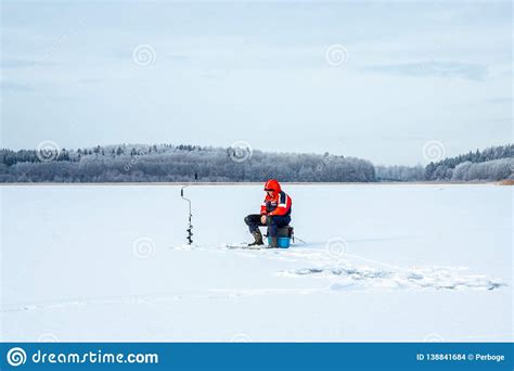 Winter Landscape View Of One Elderly Male On A Frozen Lake Ice Fishing