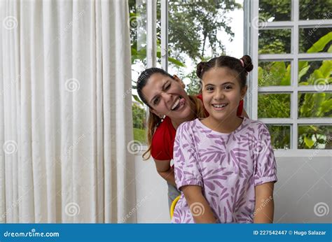 Portrait Of A Cheerful Latina Woman With Her Daughter Looking At Camera