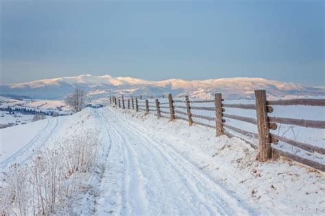 Winter Country Landscape With Timber Fence And Snowy Road Stock Photo