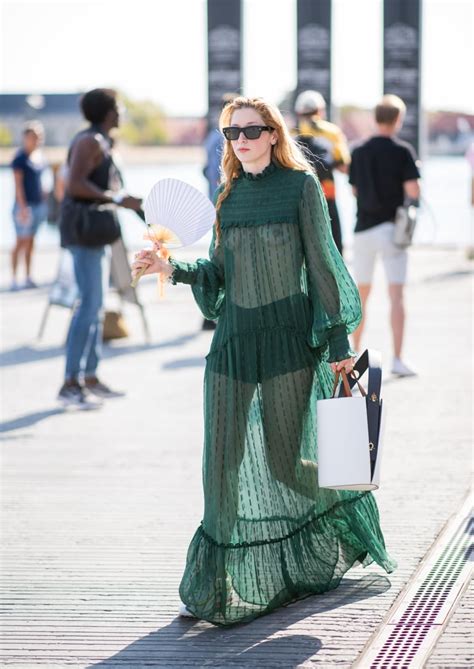a guest going braless in a sheer green dress with black shorts sheer dress trend at fashion