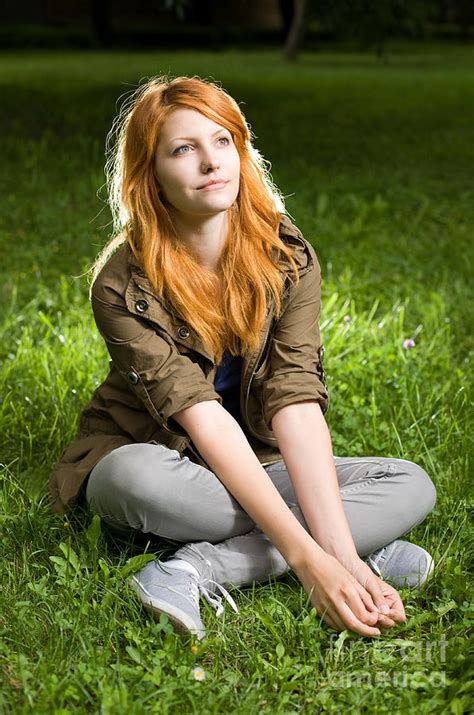 Romantic Portrait Of A Young Redhead Girl Sitting In The Park