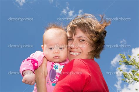 Happy Smiling Mother Holding Her Baby Daughter While Sitting On A Park