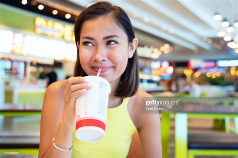 asian woman having fast food drinking with disposable cup in shopping mall food court high res